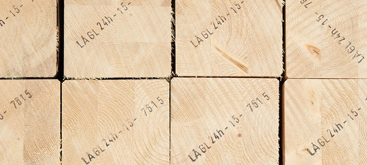 Gestapelte Brettschichtholzbalken mit sichtbarer Jahresringstruktur und Markierungen für den Holzbau.
