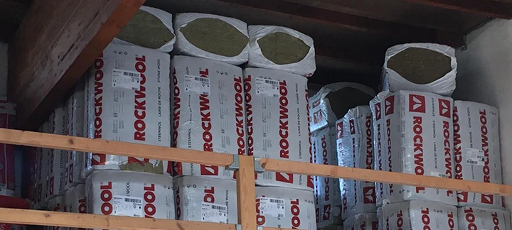 Gestapelte Pakete mit Rockwool-Dämmmaterialien in einem Lagerregal – mineralische Wärmedämmung für den Hausbau.