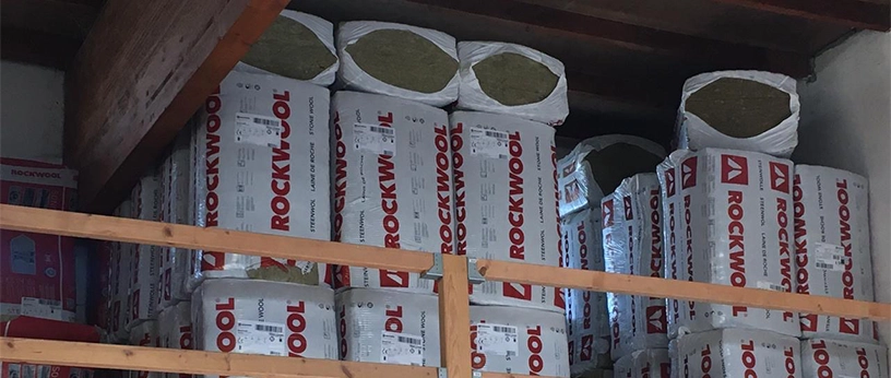 Gestapelte Pakete mit Rockwool-Dämmmaterialien in einem Lagerregal – mineralische Wärmedämmung für den Hausbau.