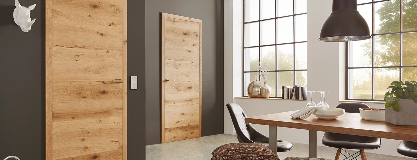 Zwei moderne Echtholztüren in Eiche in einem stilvoll eingerichteten Essbereich mit großer Fensterfront und Holztisch.